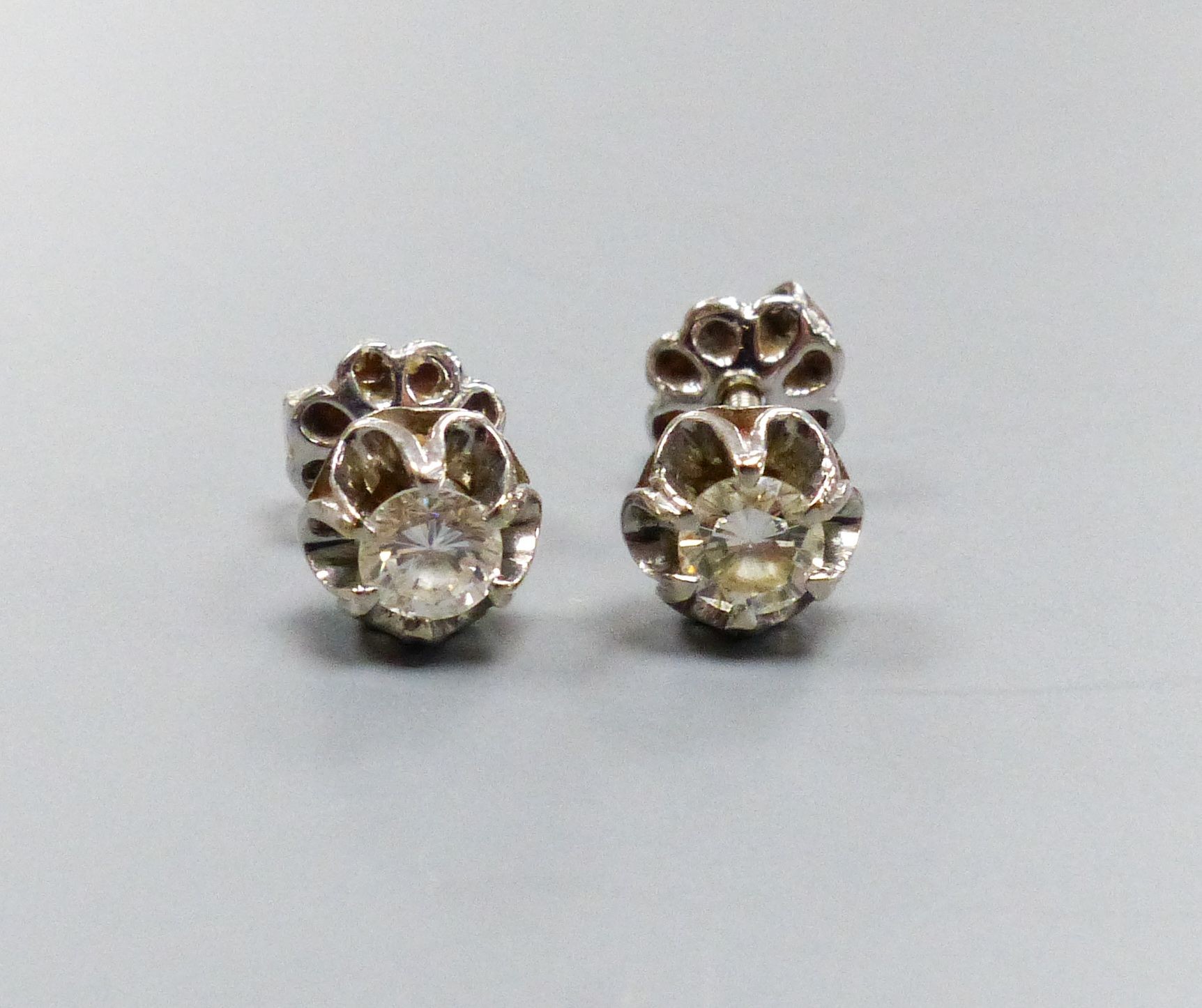 A pair of white metal and solitaire diamond set ear studs, each stone approx. 0.20ct, gross weight 2.4 grams.